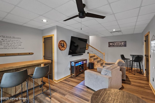 living area featuring ceiling fan, stairway, wood finished floors, and baseboards
