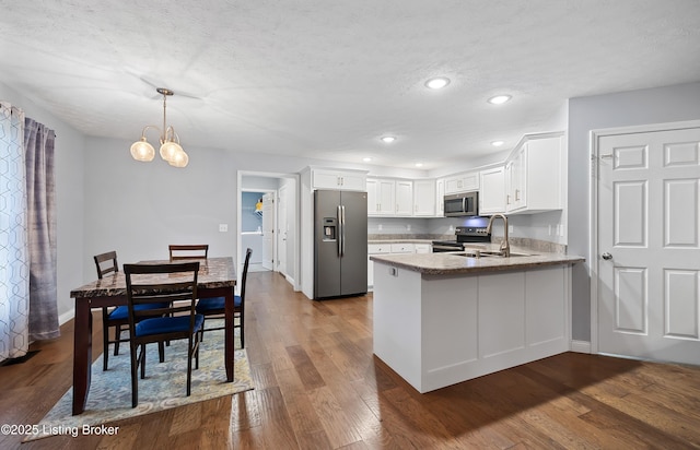 kitchen featuring dark wood-type flooring, a peninsula, white cabinetry, and appliances with stainless steel finishes