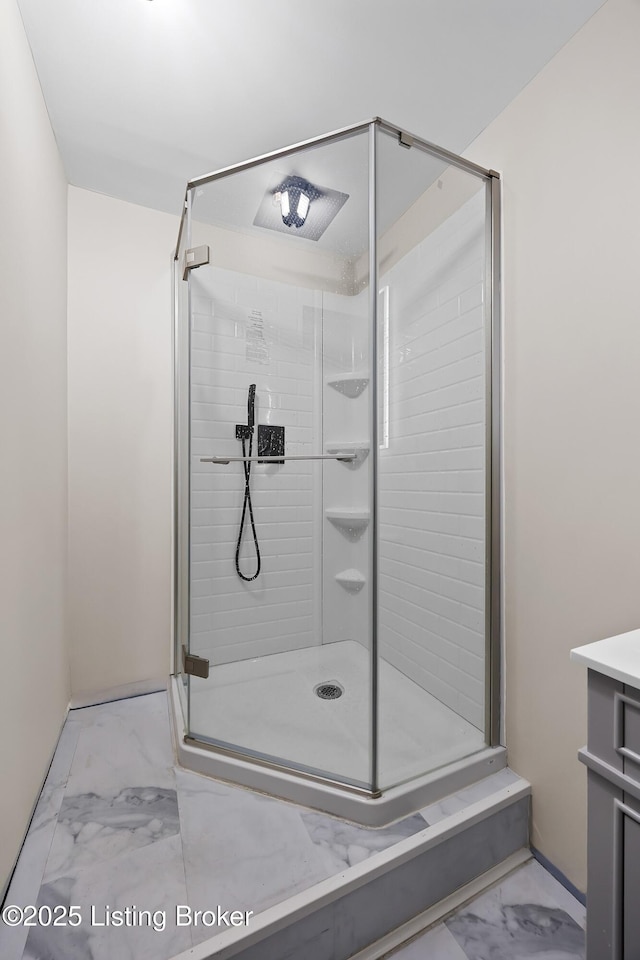 bathroom with a stall shower, marble finish floor, baseboards, and vanity