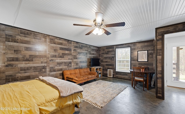 bedroom featuring wood walls and concrete flooring