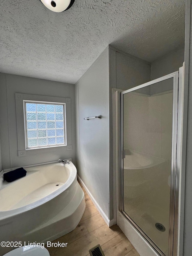 490 Blackjack Rd, Radcliff, KY 40160 - bathroom featuring a shower stall, a textured ceiling, wood finished floors, a bath, and baseboards