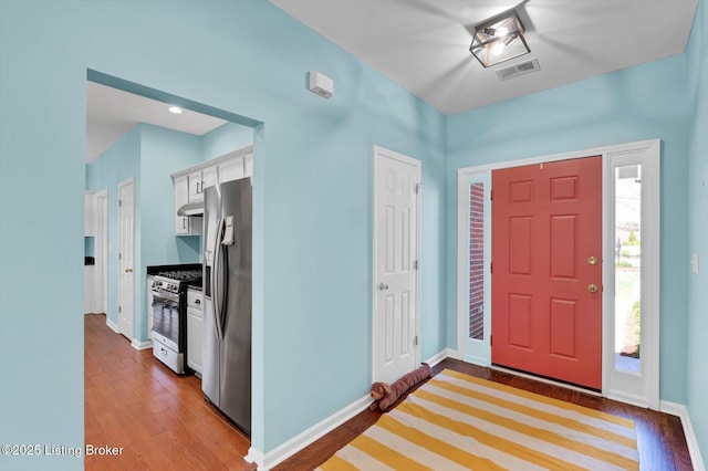 foyer entrance with dark wood-style flooring, visible vents, and baseboards