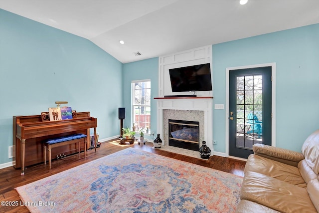 living room with plenty of natural light, a high end fireplace, visible vents, and wood finished floors