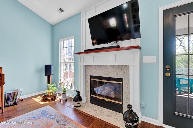 living room with wood finished floors, visible vents, a fireplace, and baseboards