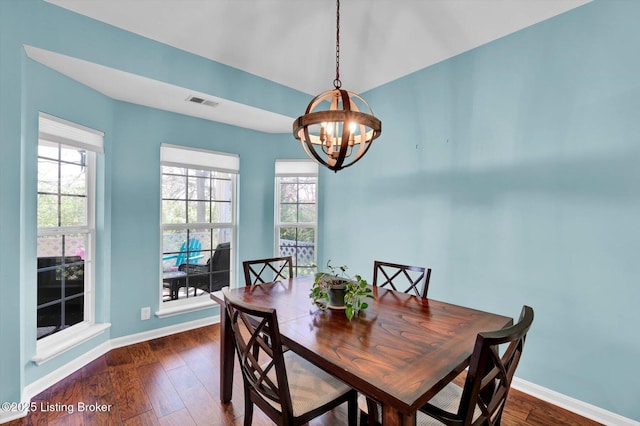 dining space featuring dark wood-style flooring, visible vents, baseboards, and a chandelier