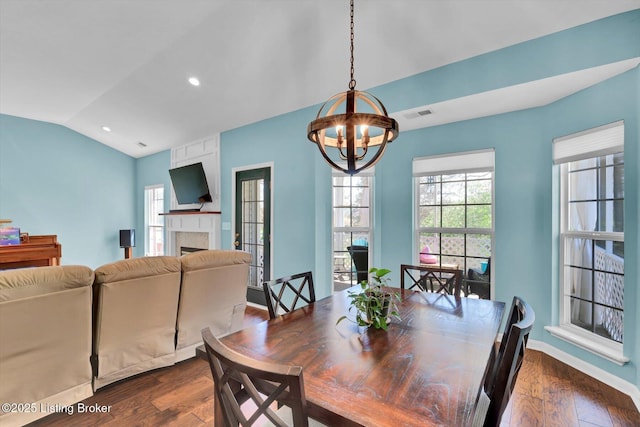 dining room with a fireplace, visible vents, vaulted ceiling, dark wood-style flooring, and a notable chandelier