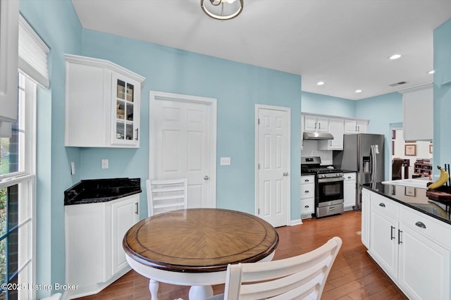 kitchen featuring dark countertops, a healthy amount of sunlight, appliances with stainless steel finishes, and under cabinet range hood