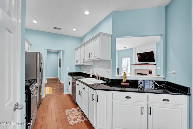 kitchen featuring white cabinetry, visible vents, decorative backsplash, stainless steel appliances, and a sink