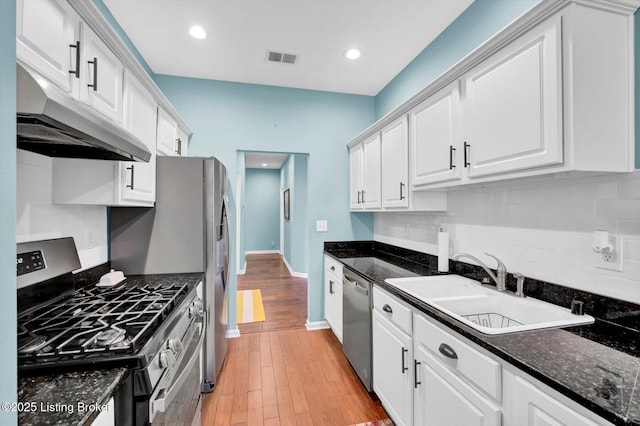 kitchen featuring white cabinets, under cabinet range hood, visible vents, appliances with stainless steel finishes, and a sink