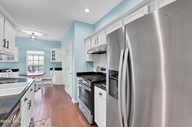 kitchen with appliances with stainless steel finishes, wood finished floors, white cabinetry, and under cabinet range hood