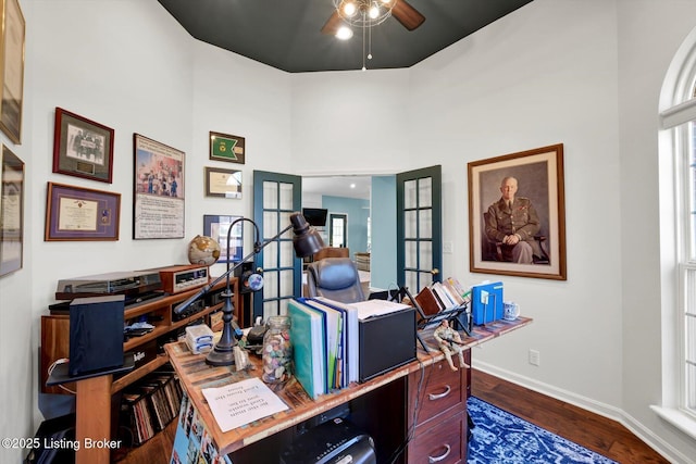 office space with dark wood-type flooring, a ceiling fan, a high ceiling, french doors, and baseboards