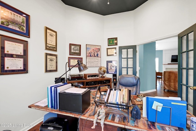 office featuring a high ceiling, wood finished floors, and baseboards