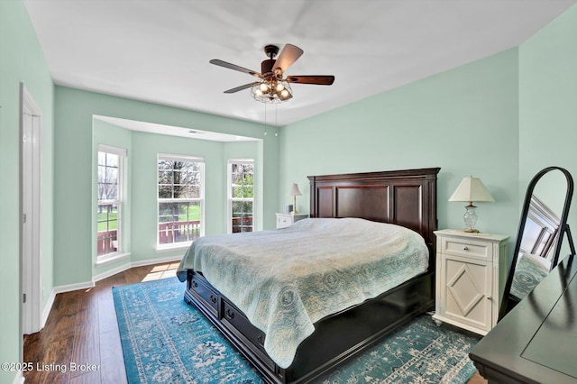 bedroom with baseboards, a ceiling fan, and dark wood-style floors