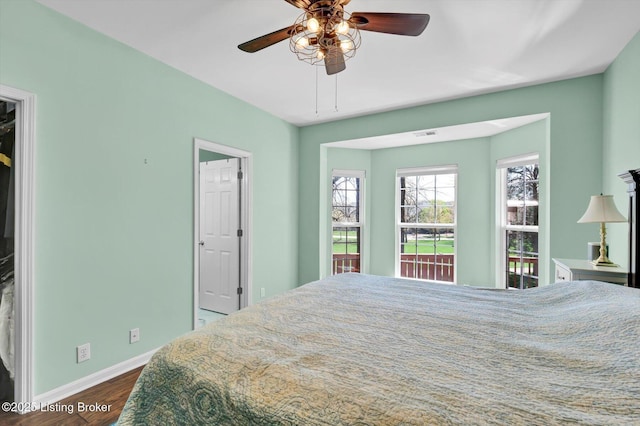 bedroom with a ceiling fan, baseboards, and dark wood finished floors