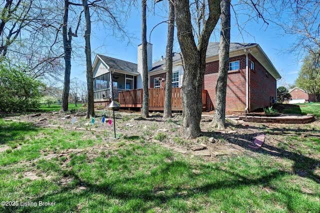 exterior space with brick siding, a wooden deck, and a sunroom
