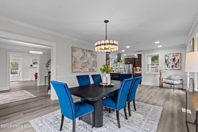 dining area with crown molding, wood finished floors, a notable chandelier, and a wealth of natural light