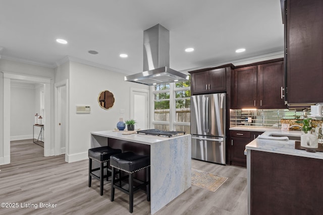 kitchen with ornamental molding, appliances with stainless steel finishes, a breakfast bar, island range hood, and a kitchen island
