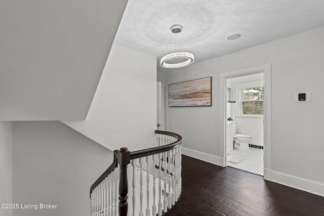 interior space featuring baseboards, an upstairs landing, a chandelier, and wood finished floors