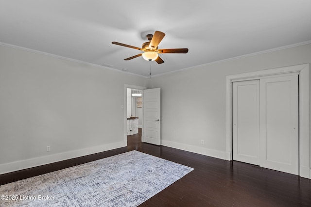 unfurnished bedroom with crown molding, baseboards, and dark wood-style floors