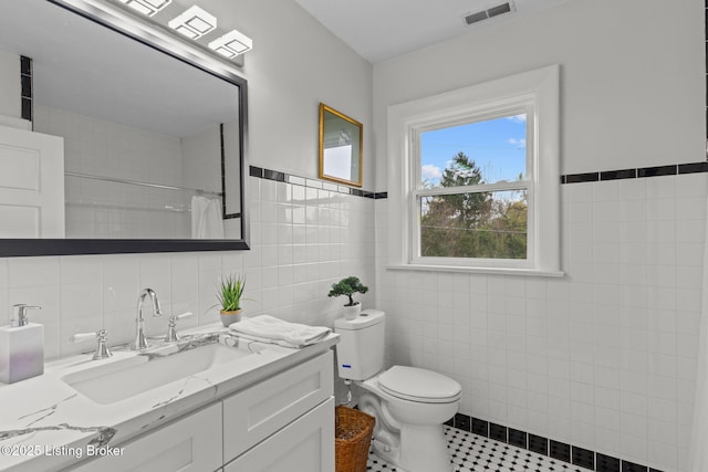 full bathroom featuring tile patterned floors, a shower with curtain, toilet, visible vents, and tile walls