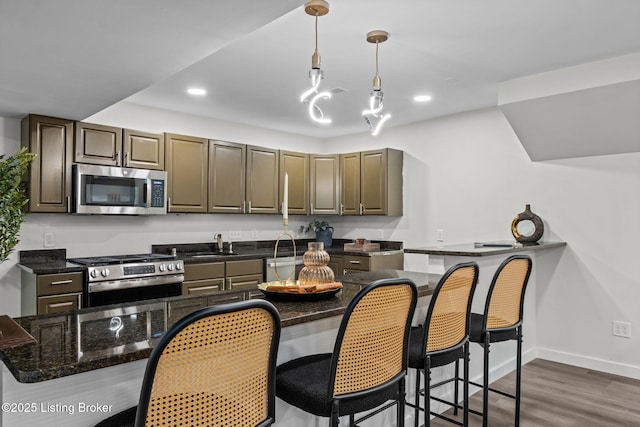 kitchen featuring pendant lighting, dark wood finished floors, a sink, stainless steel appliances, and baseboards