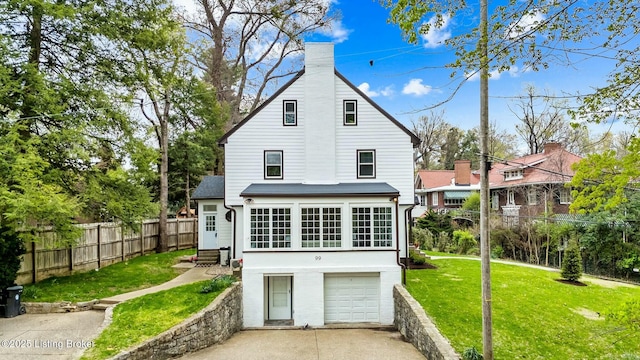 rear view of house featuring a yard, fence, an attached garage, a chimney, and driveway