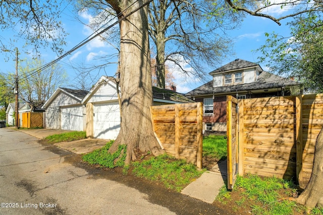 view of front of home with a garage, an outdoor structure, fence, and a gate