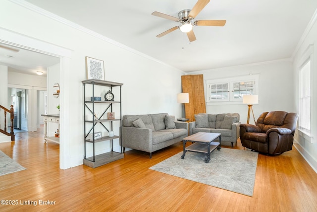 living room with light wood finished floors, ornamental molding, and ceiling fan