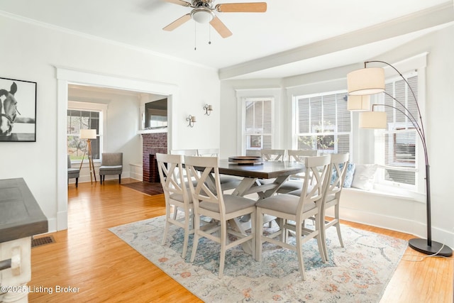 dining space featuring light wood finished floors, baseboards, crown molding, and a ceiling fan