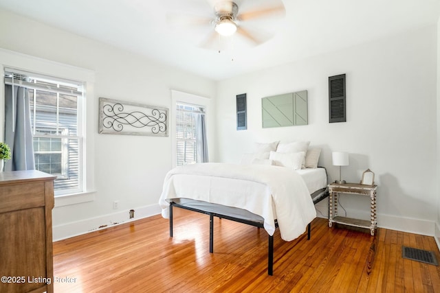 bedroom featuring ceiling fan, visible vents, baseboards, and wood finished floors