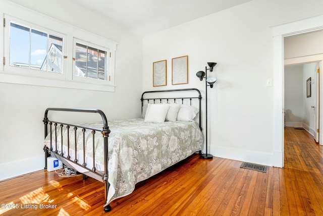 bedroom with visible vents, baseboards, and hardwood / wood-style floors