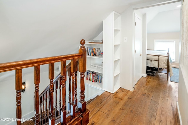 staircase with hardwood / wood-style floors and vaulted ceiling