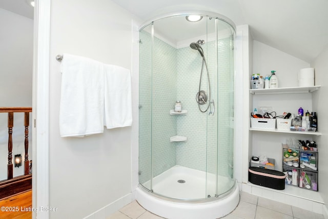 bathroom with tile patterned floors, baseboards, a stall shower, and lofted ceiling