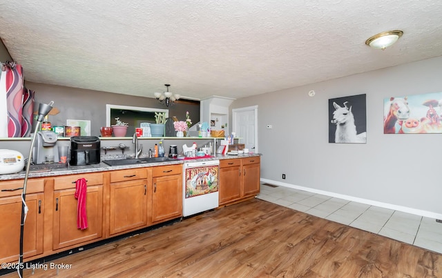 310 Wentworth Ave, Bedford, KY 40006 - kitchen featuring a notable chandelier, a sink, light wood-style floors, dishwashing machine, and brown cabinets