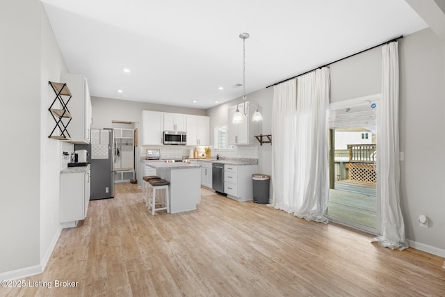 kitchen featuring a breakfast bar, white cabinetry, backsplash, a kitchen island, and appliances with stainless steel finishes