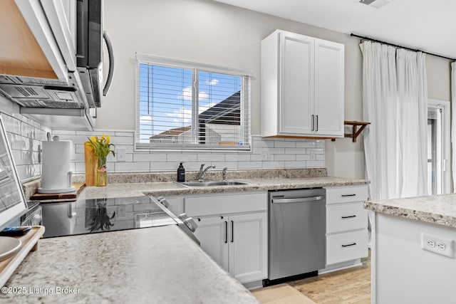 kitchen with decorative backsplash, light countertops, white cabinets, and stainless steel appliances