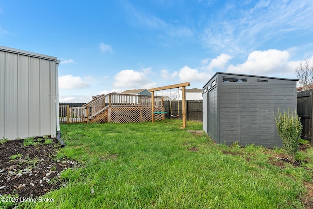 view of yard with an outbuilding, a shed, a fenced backyard, and a wooden deck