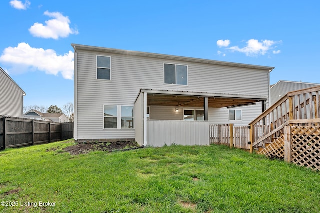 rear view of house featuring fence and a lawn