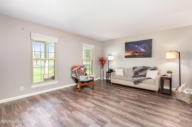 living area with wood finished floors, baseboards, and visible vents