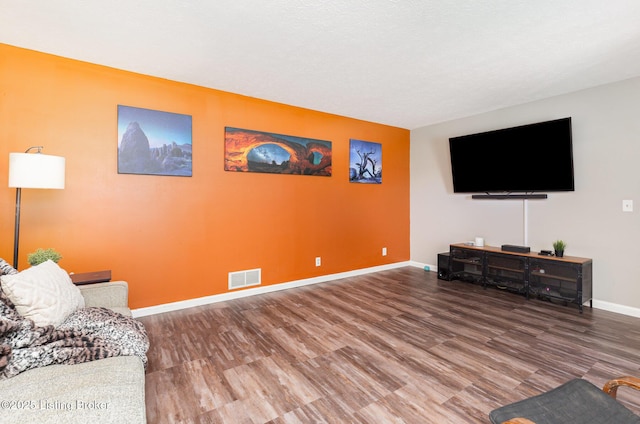 living room with visible vents, baseboards, and wood finished floors