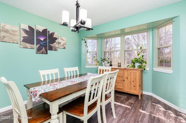 dining space featuring dark wood-type flooring, baseboards, a notable chandelier, and a textured ceiling