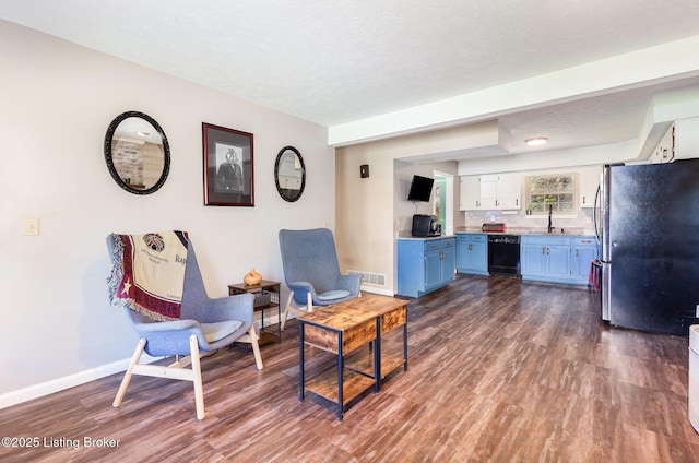 living room with dark wood-style flooring, baseboards, visible vents, and a textured ceiling