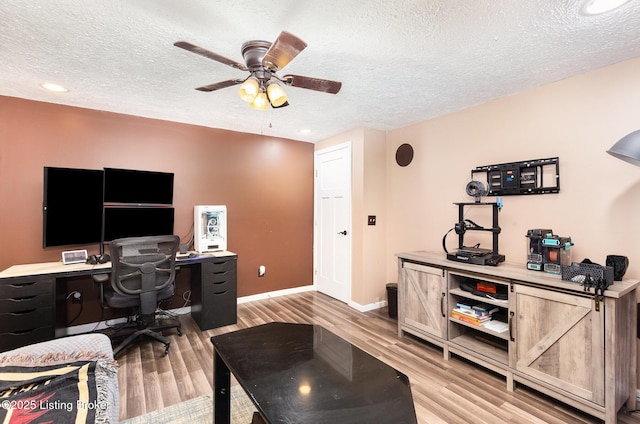 home office with light wood-style floors, a textured ceiling, baseboards, and ceiling fan
