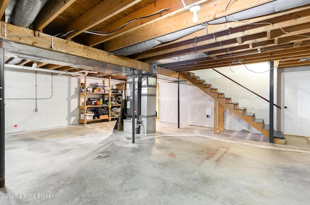 unfinished basement featuring stairway and heating unit