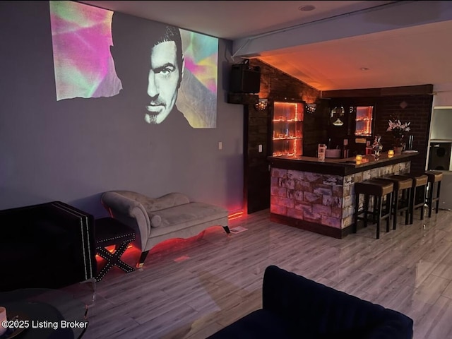 bar with wood finished floors, vaulted ceiling, and bar