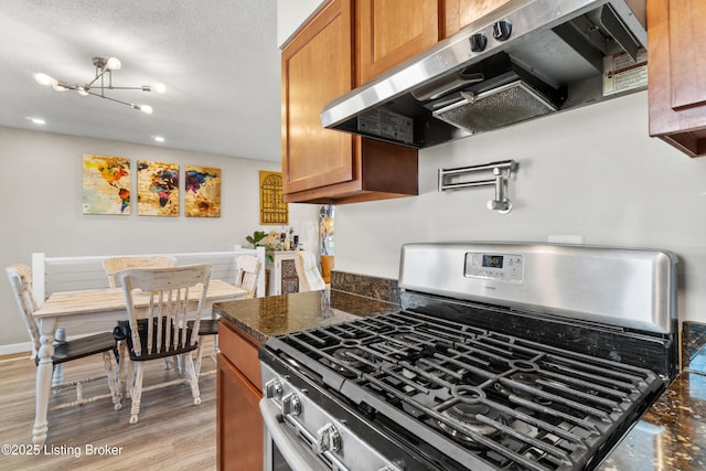 6201 Manse Dr, Louisville, KY 40258 - kitchen featuring brown cabinets, light wood-style flooring, stainless steel gas range oven, and exhaust hood