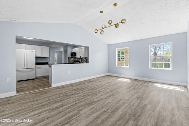 8006 Bramble Ln, Louisville, KY 40258 - unfurnished living room featuring a textured ceiling, wood finished floors, baseboards, and vaulted ceiling