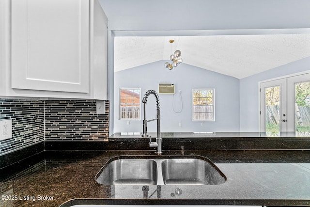 8006 Bramble Ln, Louisville, KY 40258 - kitchen featuring dark stone countertops, a sink, white cabinetry, vaulted ceiling, and backsplash
