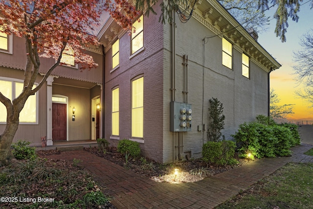 property exterior at dusk featuring brick siding