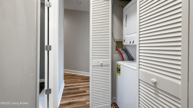 washroom featuring laundry area, stacked washer and dryer, wood finished floors, and baseboards